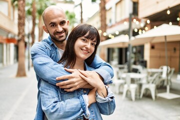 Young hispanic couple smiling happy standing at the city.