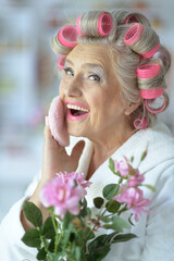 Portrait of senior woman in bathrobe applying make up