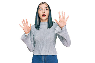Young modern girl wearing casual sweater afraid and terrified with fear expression stop gesture with hands, shouting in shock. panic concept.