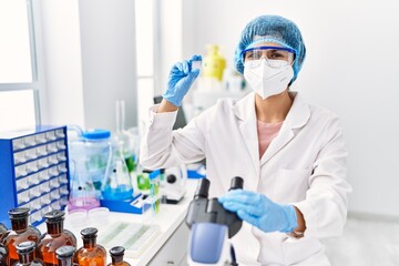 Young latin woman wearing scientist uniform working at laboratory