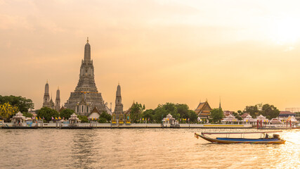 Fototapeta na wymiar Beautiful sunset landscape photo of Wat Arun temple along Chai Phra Ya river with motor boat during sunset. Arun temple is one famous landmark for tourist around the.world who come to visit Thailand.