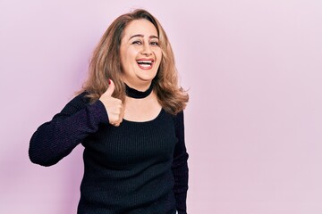 Middle age caucasian woman wearing casual clothes doing happy thumbs up gesture with hand. approving expression looking at the camera showing success.