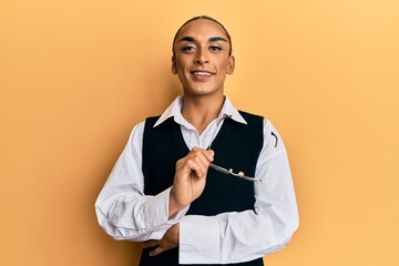 Hispanic man wearing make up and long hair wearing business shirt and glasses smiling with a happy...