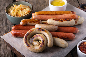Assorted grilled sausages with sauerkraut on wooden background