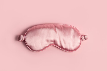 Pink silk sleeping mask on a pastel pink background