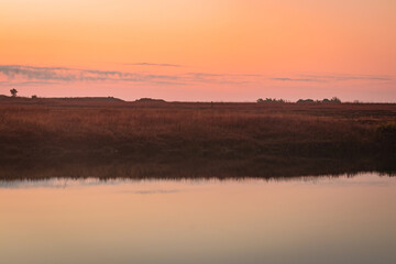 Obraz na płótnie Canvas calm lake with dramatic sunrise orange sky reflection at morning