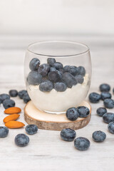 Sweet dessert in glass with fresh blueberries and whipped cream on white background
