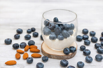 Sweet dessert in glass with fresh blueberries and whipped cream on white background
