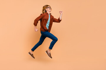 Fototapeta na wymiar Full length body size view of attractive cheerful anergetic guy jumping running bargain isolated over beige pastel color background