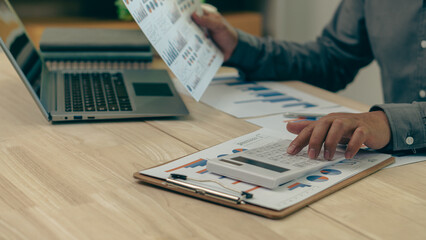 Businessman's hands pressing a calculator, calculating, analyzing, graphing, charting, accounting worker working on a laptop. A bank clerk who advises making financial reports or company profits.