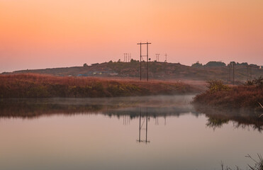 Fototapeta na wymiar calm lake with dramatic sunrise orange sky reflection at morning