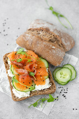 sandwich with salted salmon, cucumber and curd cheese on a gray table