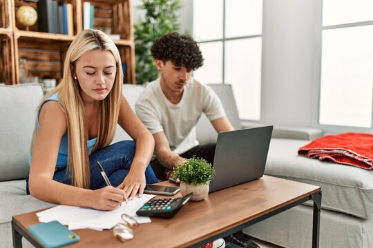 Young Couple With Serious Expression Controlling Family Economy At Home.