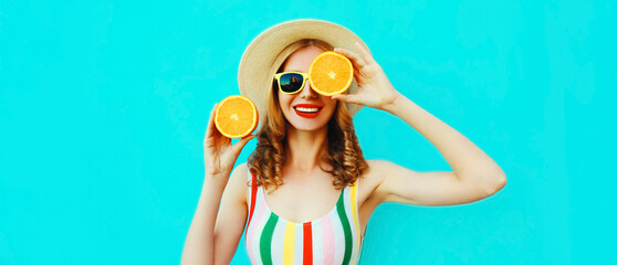 Summer portrait of happy smiling young woman with fresh slices of orange fruits wearing straw hat,...
