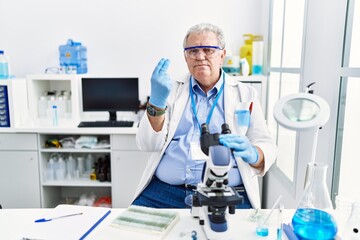Senior caucasian man working at scientist laboratory doing italian gesture with hand and fingers confident expression