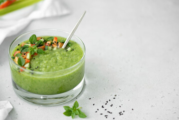 chilled cucumber gazpacho with tomato pieces and basil in a glass bowl, copy space