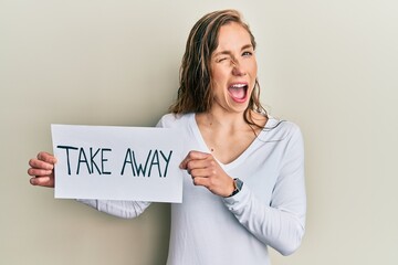 Young blonde woman holding take away food winking looking at the camera with sexy expression,...