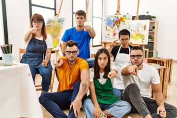 Group of people sitting at art studio pointing with finger to the camera and to you, confident gesture looking serious