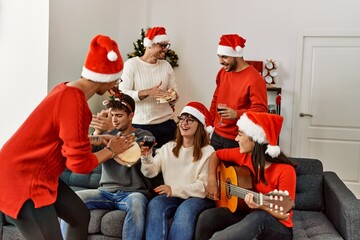 Group of young people celebrating christmas singing carol song at home.