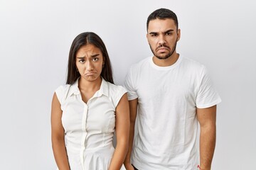 Obraz premium Young interracial couple standing together in love over isolated background depressed and worry for distress, crying angry and afraid. sad expression.