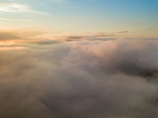 The rays of dawn over the fog in the Ukrainian Carpathians. Aerial drone view.