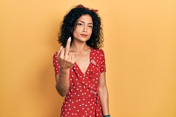 Young latin girl wearing summer dress showing middle finger, impolite and rude fuck off expression