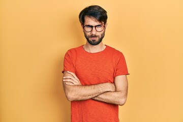 Fototapeta premium Young hispanic man wearing casual clothes and glasses skeptic and nervous, disapproving expression on face with crossed arms. negative person.