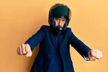 Middle age hispanic man wearing motorcycle helmet doing moto symbol with hands depressed and worry...