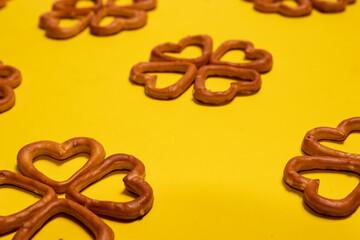 Heart-shaped salty pretzels on yellow background 