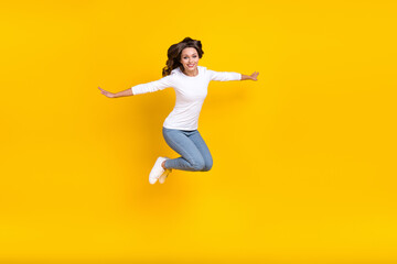 Fototapeta na wymiar Photo of shiny sweet woman wear white shirt jumping arms sides running isolated yellow color background