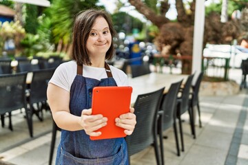 Young down syndrome woman wearing apron using touchpad at coffee shop terrace - obrazy, fototapety, plakaty