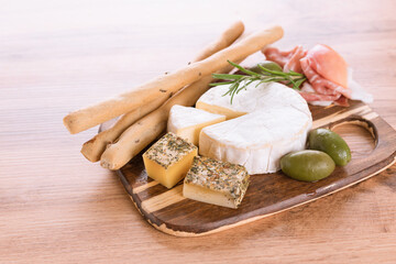 Solid and soft-ripened cheeses served with prosciutto, olives and grissini - bread sticks....