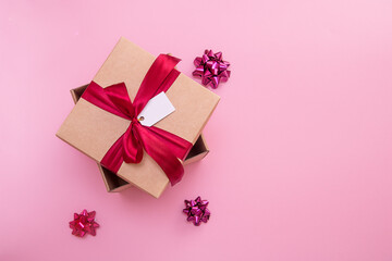 gift box with satin bow and tag on pink background