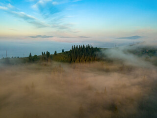 Obraz premium The rays of dawn over the fog in the Ukrainian Carpathians. Aerial drone view.
