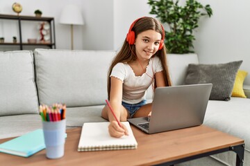 Adorable girl doing homework using laptop at home