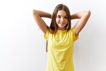 Young brunette teenager standing together over isolated background relaxing and stretching, arms and hands behind head and neck smiling happy