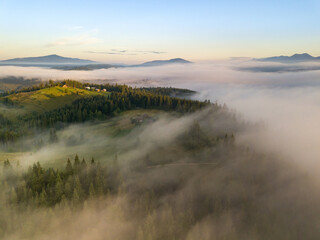 The rays of dawn over the fog in the Ukrainian Carpathians. Aerial drone view.