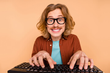 Portrait of handsome trendy cheery red-haired guy writing html tech solution isolated over beige pastel color background