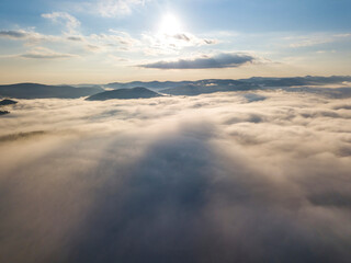 Obraz premium Flight over fog in Ukrainian Carpathians in summer. Mountains on the horizon. A thick layer of fog covers the mountains with a continuous carpet. Aerial drone view.