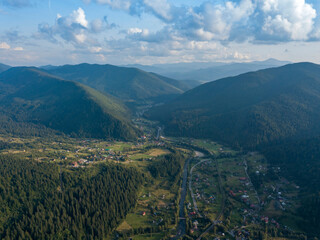 Green slopes of Ukrainian Carpathian mountains in summer. Cloudy day, low clouds. Aerial drone view.