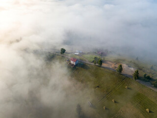 Naklejka premium Mountain settlement in the Ukrainian Carpathians in the morning mist. Aerial drone view.