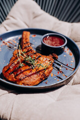 Grilled tomahawk beef steak, with berry sauce, herbs and spices on a blue plate