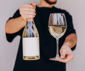Man's hand holding glass and bottle of white wine