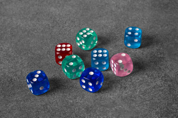Multi-colored dice on a concrete background.