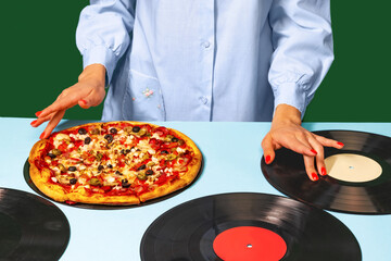 Food pop art photography. Female hands with italian pizza lying on vinyl discs on light tablecloth isolated on green background. Vintage, retro style fashion, music
