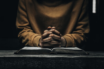 Fototapeta premium Women pray for God's blessings for a better life. Christian Life Crisis Prayer to God . Human hands pray to God with Scriptures. Believe in the good. Hold hands in prayer on a wooden table.