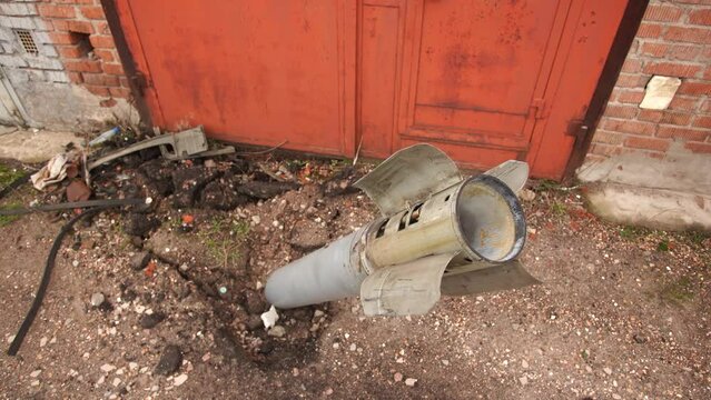 Close-up view 4k stock video footage of real unexploded military missile, torpedo or shell stuck in ground near doors of garages outdoors. Moments of dreadful war of Russia against Ukraine in 2022