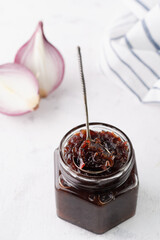 onion marmalade (Onion confiture). onion confit in a glass jar on a white background.