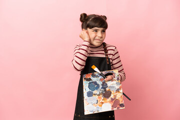 Little artist girl holding a palette isolated on pink background frustrated and covering ears