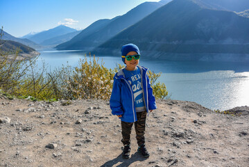 A little boy on the background of the landscape of the Zhinvali reservoir. Georgian military road. April 2019 Georgia.